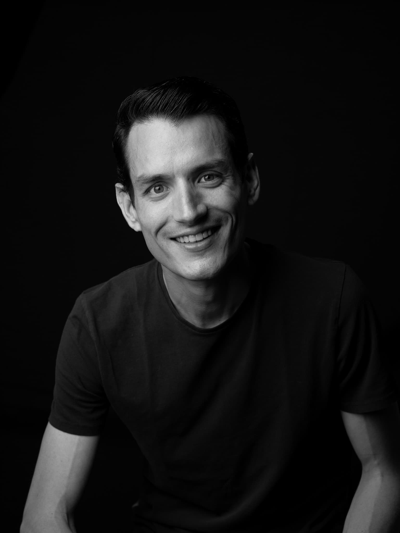 Retrato de estudio en blanco y negro de Sebastián Delsalto sobre fondo negro.